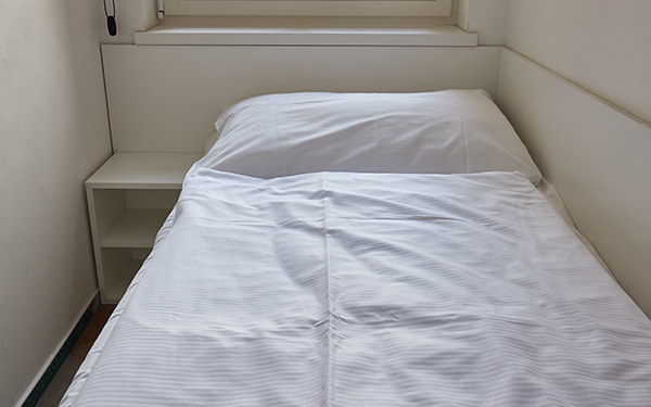 Ein einfaches Bett in einem schmalen Raum